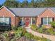 Inviting red brick home with a red front door, black shutters, and lush landscaping at 522 Plantation Creek Dr, Loganville, GA 30052