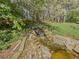 Backyard water feature with a small waterfall set amongst mature trees and lush greenery makes you feel one with nature at 522 Plantation Creek Dr, Loganville, GA 30052
