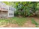 View of backyard showing trees and small green plantings, with back of townhome in background at 4912 Waters Edge Trl, Roswell, GA 30075
