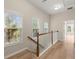 Hallway with wood floors, white railings, and lots of natural light from three windows at 4912 Waters Edge Trl, Roswell, GA 30075