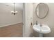 Convenient powder room with pedestal sink, decorative mirror, and adjacent dining area at 4912 Waters Edge Trl, Roswell, GA 30075