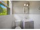 Compact bathroom with a gray vanity, toilet, tiled walls, and a window for natural light at 4861 Alcan Rd, Powder Springs, GA 30127