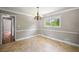 Traditional dining room featuring paneled walls, neutral colors, a chandelier, and a window for natural light at 4861 Alcan Rd, Powder Springs, GA 30127