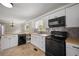 Updated kitchen with a mosaic backsplash, white cabinets, and black appliances at 4861 Alcan Rd, Powder Springs, GA 30127