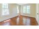 Empty bedroom featuring three windows for abundant natural light and hardwood floors at 5201 Skyline Dr, Stone Mountain, GA 30083