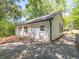 Shows the side of a white home with a dark roof, small windows, and a driveway and partial yard with mature trees at 5201 Skyline Dr, Stone Mountain, GA 30083