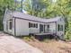 Charming home with white siding, a dark roof, and updated windows, on a wooded lot with driveway at 5201 Skyline Dr, Stone Mountain, GA 30083