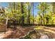 Spacious backyard with mature trees and a stone retaining wall, offering a peaceful and private outdoor setting at 5272 Cumberland Way, Stone Mountain, GA 30087