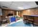 Spacious basement with wood paneled walls, drop ceiling, a wet bar, blue floor and neutral colored sofa at 5272 Cumberland Way, Stone Mountain, GA 30087
