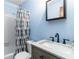 Bathroom with light blue walls, marble sink, black faucet, tub with shower and colorful shower curtain at 5272 Cumberland Way, Stone Mountain, GA 30087
