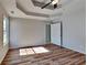 Bright main bedroom with tray ceiling, ceiling fan and wood-look flooring at 145 Charleston Pl, Covington, GA 30016
