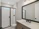 Modern bathroom features a glass shower and vanity with a dark framed mirror at 2013 Ripple Park Bnd, Canton, GA 30114