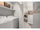 Bright laundry room with washer, dryer, and storage shelves adjacent to the living area at 2014 Anchor Way, Buford, GA 30518