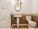 Half-bathroom with pedestal sink, oval mirror, and wood-look flooring at 4272 Glenlake Nw Dr, Kennesaw, GA 30144