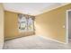 Bedroom featuring yellow walls, carpet flooring, and a window overlooking a residential street at 4272 Glenlake Nw Dr, Kennesaw, GA 30144