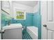 Retro-style bathroom featuring blue tile, white fixtures, and a window providing natural light at 851 Rockbridge Sw Rd, Lilburn, GA 30047