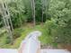 Backyard with a covered wooden patio, an empty swimming pool, and some lawn furniture surrounded by woods and lush greenery at 881 Rockbridge Sw Rd, Lilburn, GA 30047