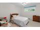 Cozy bedroom includes a neatly made bed, wooden dresser, and workspace bathed in natural light from the window at 881 Rockbridge Sw Rd, Lilburn, GA 30047