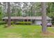 Charming single-story home with lush front lawn and mature trees in a peaceful setting at 881 Rockbridge Sw Rd, Lilburn, GA 30047