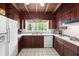 Bright kitchen with wood ceiling, white appliances, wood cabinets, and window view at 881 Rockbridge Sw Rd, Lilburn, GA 30047