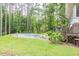 Backyard pool with diving board surrounded by mature trees and green grass at 881 Rockbridge Sw Rd, Lilburn, GA 30047