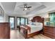 Spacious main bedroom with a tray ceiling, ceiling fan, wood floors, and a large wooden bed frame at 10005 Lakeview Pkwy, Villa Rica, GA 30180