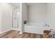 Bathroom featuring a separate shower and soaking tub, complemented by stylish wood-look flooring at 2851 Fareed St, Douglasville, GA 30135