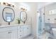 Bright bathroom featuring a double vanity with oval mirrors and a modern glass-enclosed shower at 1934 Westwood Sw Ave, Atlanta, GA 30310