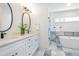 Bathroom featuring double vanity sinks, modern fixtures, stylish tile flooring, glass shower, and soaking tub at 1934 Westwood Sw Ave, Atlanta, GA 30310
