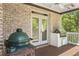 Covered porch featuring brick walls, a grill, and view of a treed backyard at 560 Brook Manor Dr, Johns Creek, GA 30022