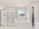 Bright, modern bathroom with white tile, glass shower, and soaking tub with natural light at 7162 Linden Dr, South Fulton, GA 30349