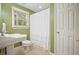Green-walled bathroom featuring a pedestal sink, toilet, and tub with a decorative white shower curtain at 210 Malvern Pl, Roswell, GA 30076