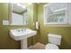 A light-filled bathroom with a pedestal sink, toilet, and large mirror at 210 Malvern Pl, Roswell, GA 30076