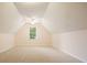 Unfurnished bonus room features pitched ceilings, a central window, neutral carpeting, and updated ceiling fan at 210 Malvern Pl, Roswell, GA 30076
