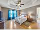 Bright main bedroom featuring a trey ceiling, king-size bed, hardwood floors, and large window with blue curtains at 502 Owens Springs Ln, Mcdonough, GA 30252