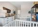 Bright Bedroom with neutral walls, two cribs, and a modern dresser with fun accessories at 26 Kensington St, Kingston, GA 30145