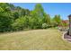 Expansive backyard featuring a lush lawn, mature trees, and a pergola-covered seating area at 6565 Bentley Ridge Dr, Cumming, GA 30040