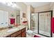 Bathroom with glass shower, granite vanity, framed mirror, and red decorative accents at 6565 Bentley Ridge Dr, Cumming, GA 30040