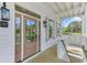 Inviting covered porch with neutral shutters, glass paned front door and sconce lighting at 1304 Six Sisters St, Dacula, GA 30019