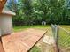 Spacious backyard with a wooden patio, chain link fence, storage shed, and mature trees at 4030 Hiram Ct, Powder Springs, GA 30127