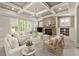 Sunlit living room showcasing a stone fireplace, coffered ceilings and lots of comfortable seating at 1286 Whisper Cove Dr, Buford, GA 30518