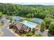 Aerial view of community pool, tennis courts, clubhouse, playground, parking, and extensive green space at 1286 Whisper Cove Dr, Buford, GA 30518
