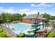 Relaxing community pool area with a waterslide, lounge chairs, tables, and umbrellas with the clubhouse in the background at 1286 Whisper Cove Dr, Buford, GA 30518