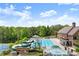 Community pool with a slide, lounge chairs, tables, umbrellas, and splash pad, with a tennis court and clubhouse nearby at 1286 Whisper Cove Dr, Buford, GA 30518