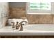 Close-up of a modern bathtub with stylish fixtures and tiled backsplash at 1286 Whisper Cove Dr, Buford, GA 30518
