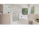 Bathroom featuring a glass enclosed shower, a soaking tub by a window, and white tiling at 470 W Magnolia Cir, Johns Creek, GA 30005