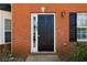 Close-up of a black front door with sidelight, showcasing a traditional brick facade and exterior lighting at 7712 Autry Circle # 204, Douglasville, GA 30134