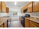 Functional kitchen equipped with wooden cabinets, black appliances, and views of a living area at 7712 Autry Circle # 204, Douglasville, GA 30134