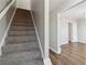 Carpeted staircase adjacent to an open doorway and hardwood floors, connecting the home's levels at 7712 Autry Circle # 204, Douglasville, GA 30134