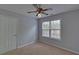 This bedroom has neutral walls and carpet, a large window, and a ceiling fan at 1080 Smoke Hill Ln, Hoschton, GA 30548
